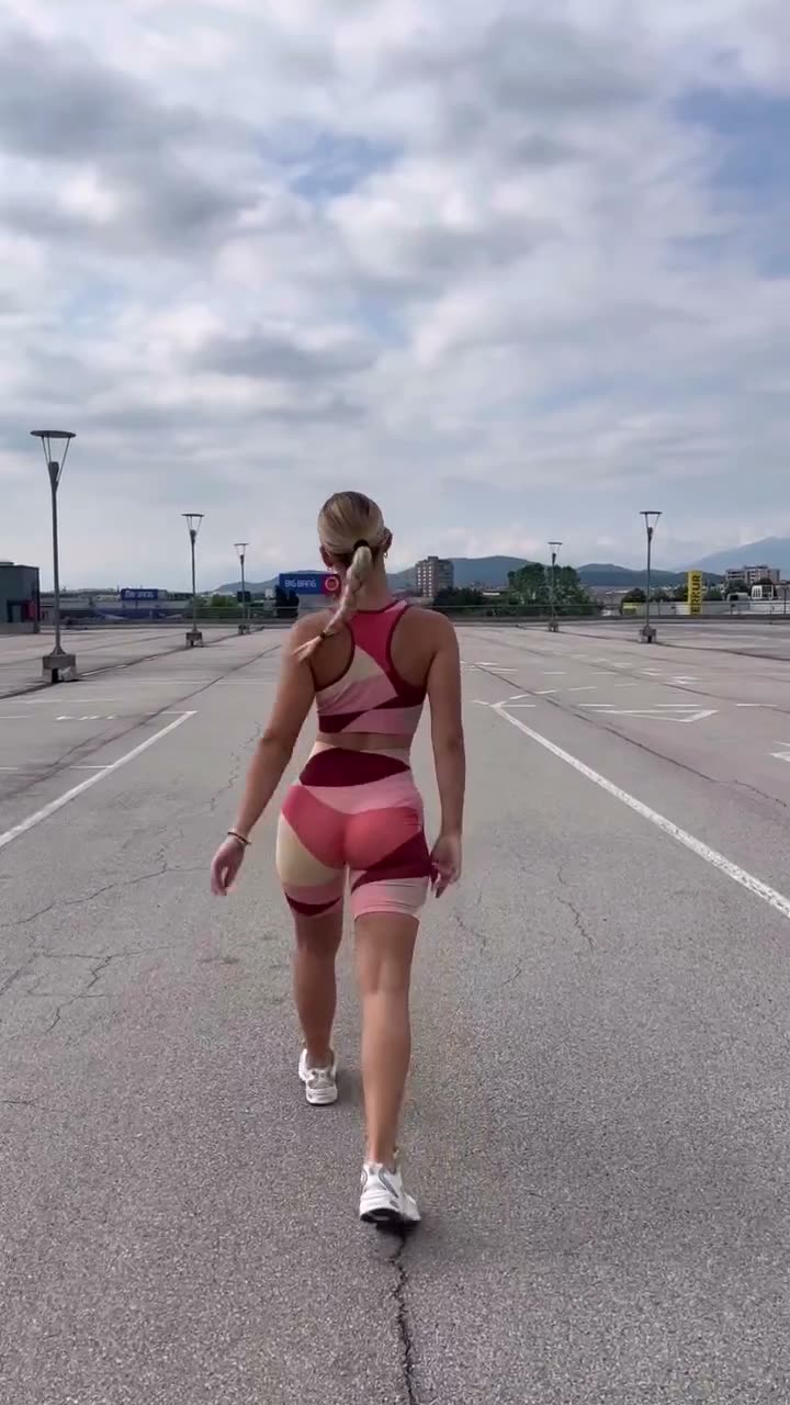 A vertical UGC ad for the brand's activewear: a creator shows a macro shot of the wordmark on the fabric, then walks away across an empty rooftop lot under a dramatic sky.