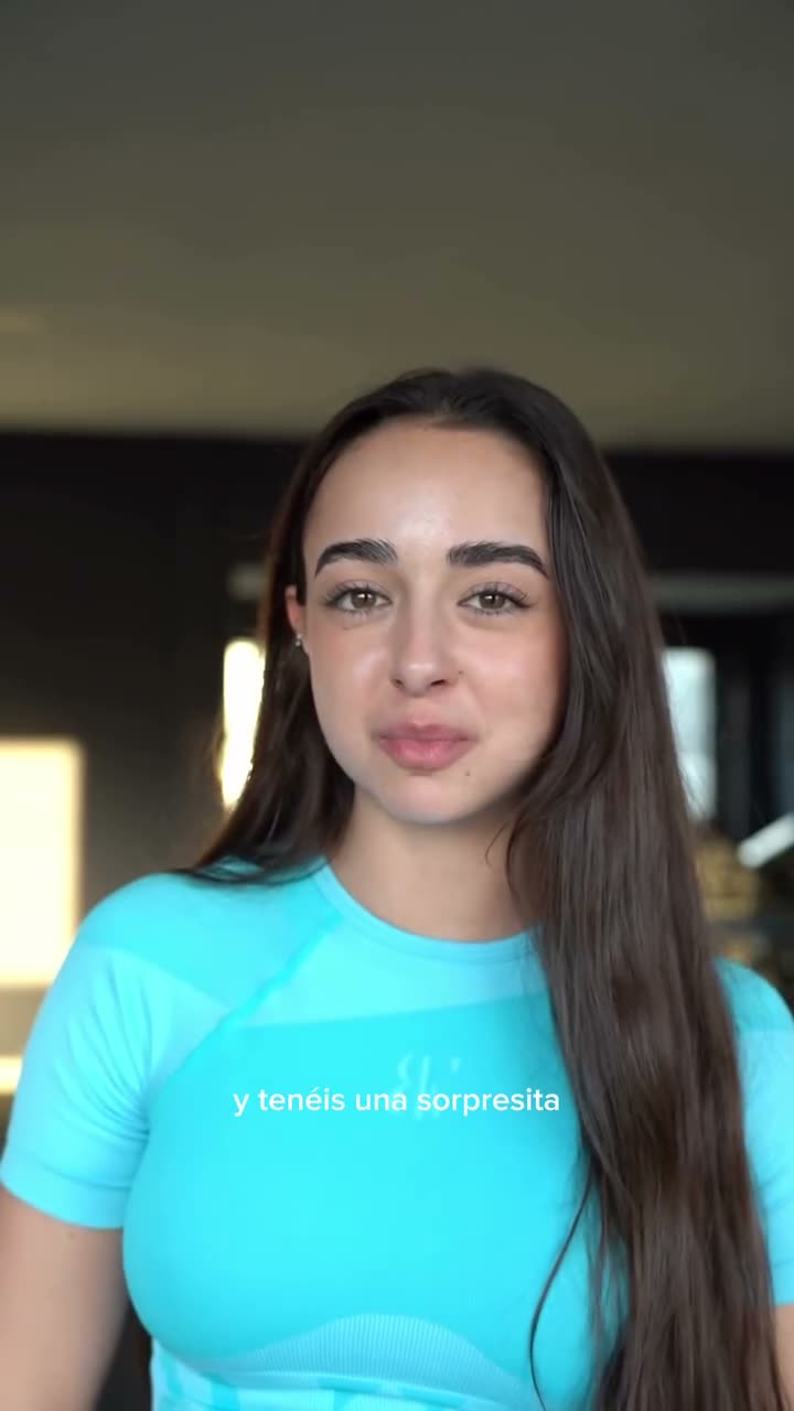 A vertical gym reel with burned-in Spanish captions: a creator in the brand's teal set talks to camera between sets, then demonstrates an exercise on a gym bench.