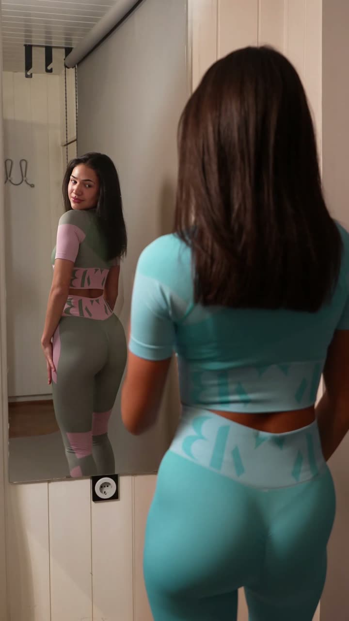 A vertical UGC ad in a fitting-room mirror: a creator in the brand's teal set turns to show the back of the fit, wordmark waistband visible.