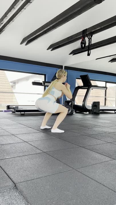 A raw handheld phone clip from the brand's creator program: one unbroken take of a creator doing dumbbell squats in a bright gym, camera drifting.